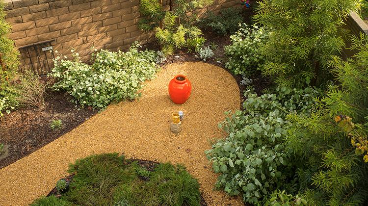 Photo of a drought-tolerant garden with a planter in the middle of the garden path.